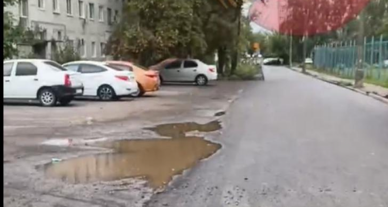 В Курске заасфальтировали дорогу у школы в дождь: провалились люки и исчезли съезды для колясок